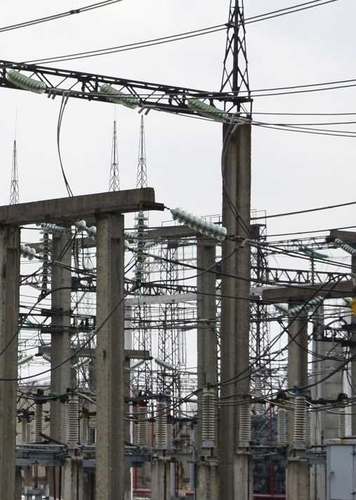 A complex electrical substation with concrete support structures, insulators, and a network of power lines.