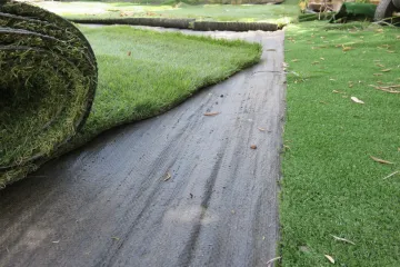 A person laying sod next to a pool.