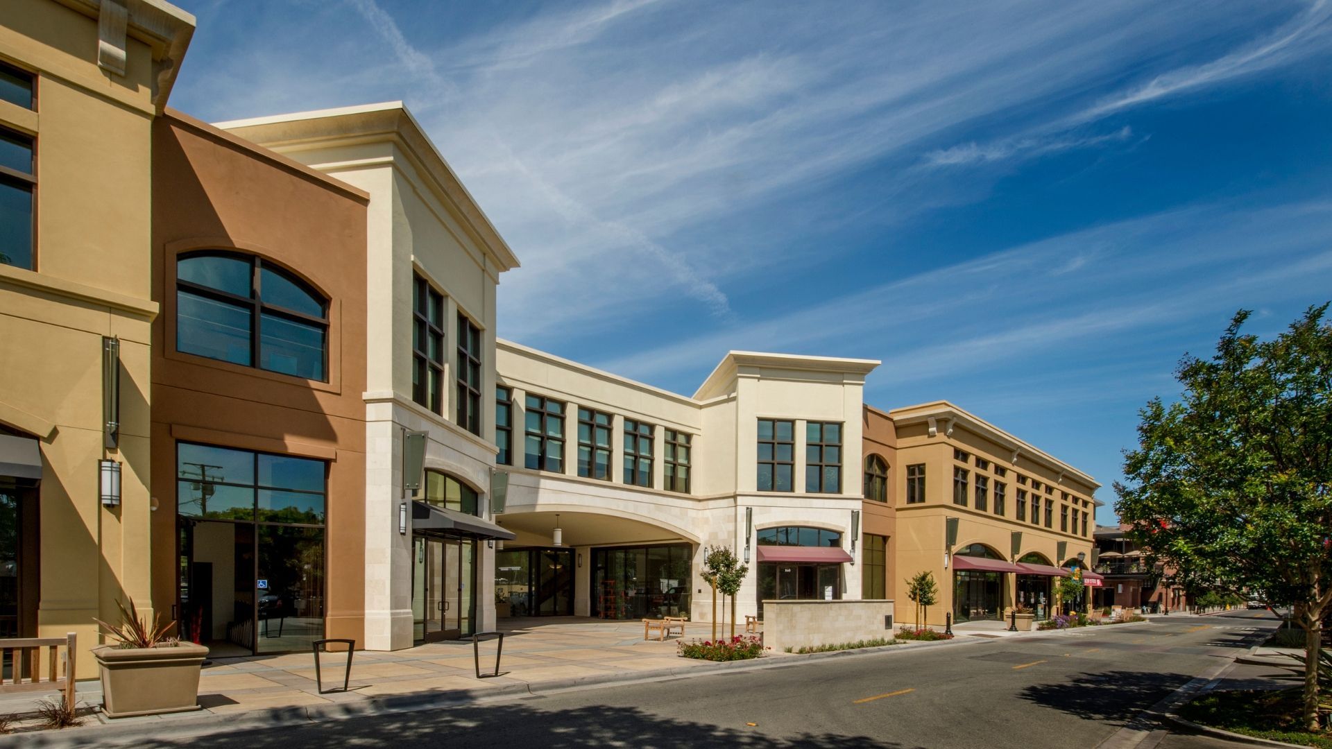 Row of modern storefronts with large windows along a sunny street under a blue sky