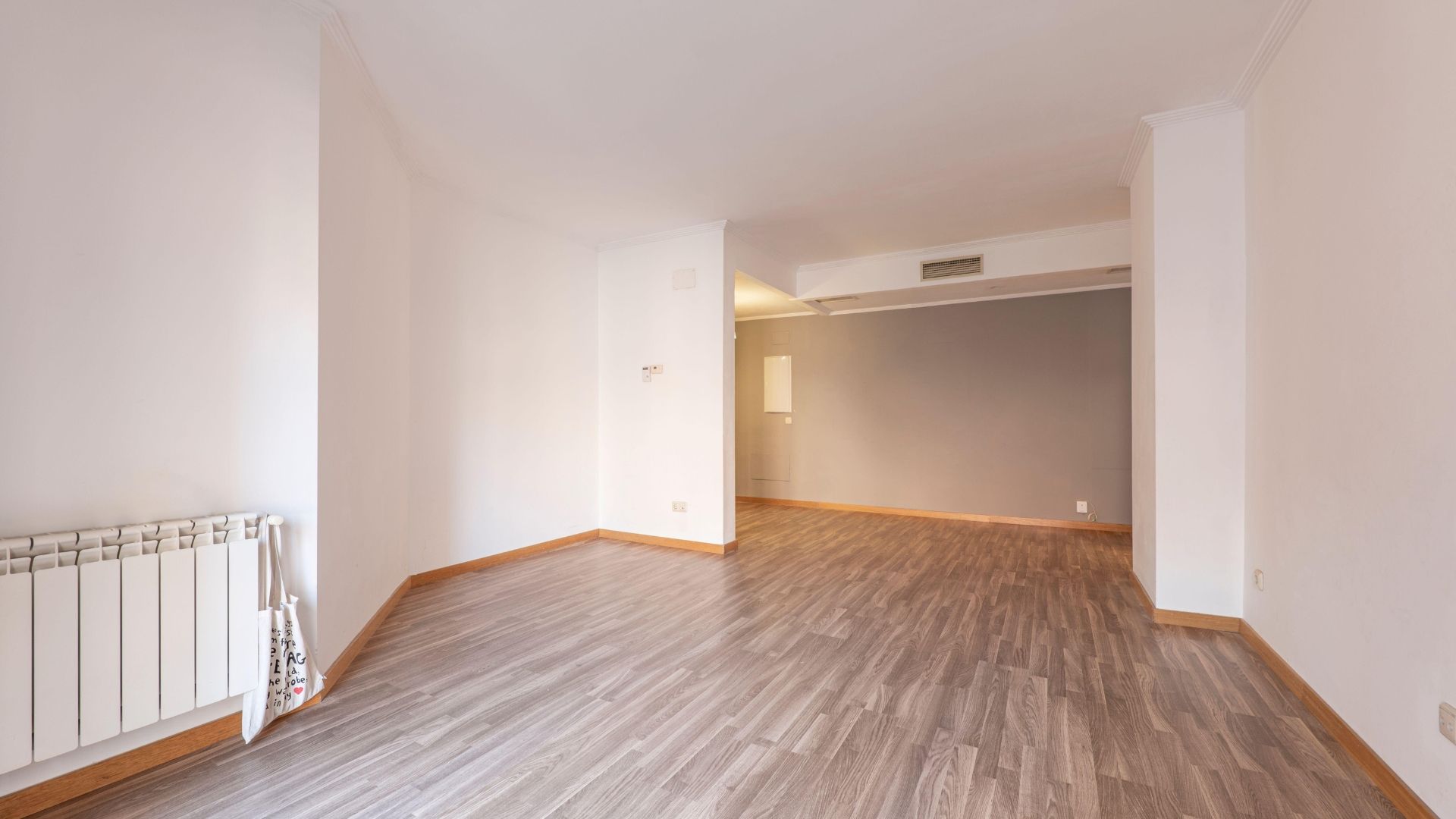 Empty unfurnished living room with wood flooring and a large open doorway to another room