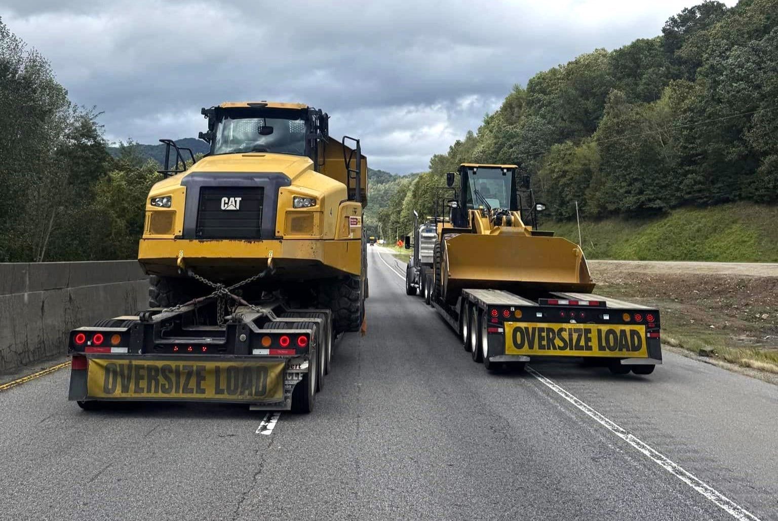 A truck is carrying a bulldozer and a dump truck on a highway.