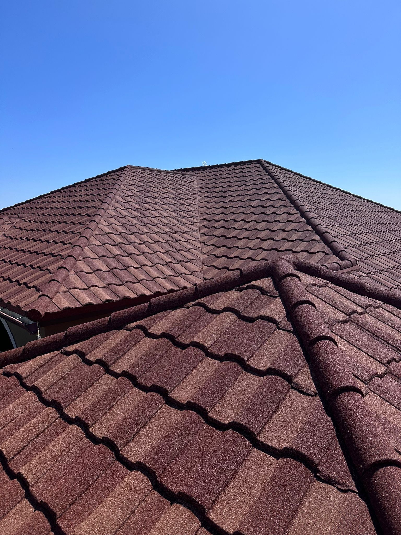 Close-up of a red textured roof against a clear blue sky.