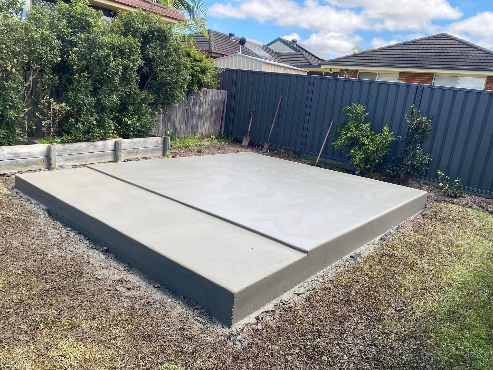 Concrete slab in a backyard, surrounded by grass, fencing, and bushes — Rhyno’s Concreting In Old Bar, NSW