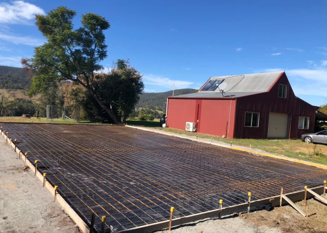 Concrete Foundation with Rebar Mesh Laid, Ready for Pouring. Red Building and Tree in The Background — Rhyno’s Concreting In Old Bar, NSW