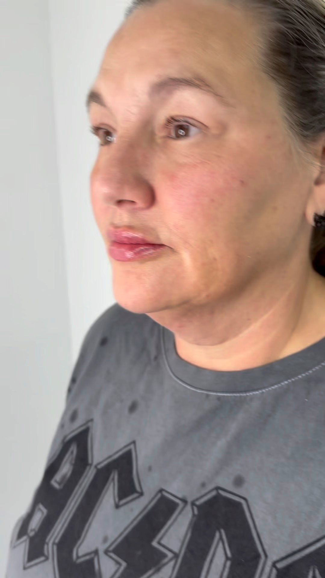 A close up of a woman 's face wearing a gray ac dc t-shirt.