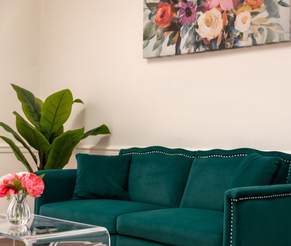 A living room with a green couch and a painting on the wall