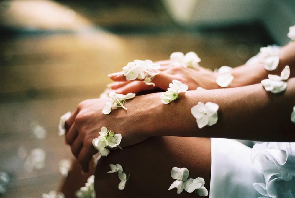 A woman is sitting on the floor with flowers on her legs.