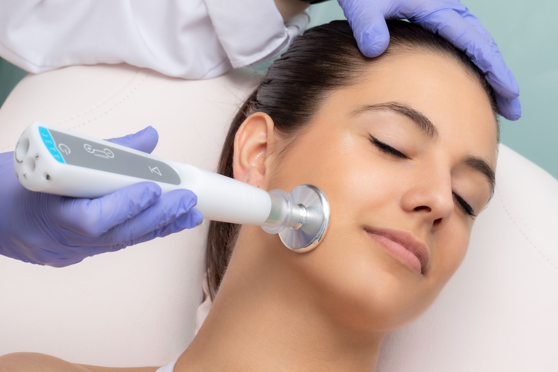 A woman is getting an ultrasound treatment on her face.