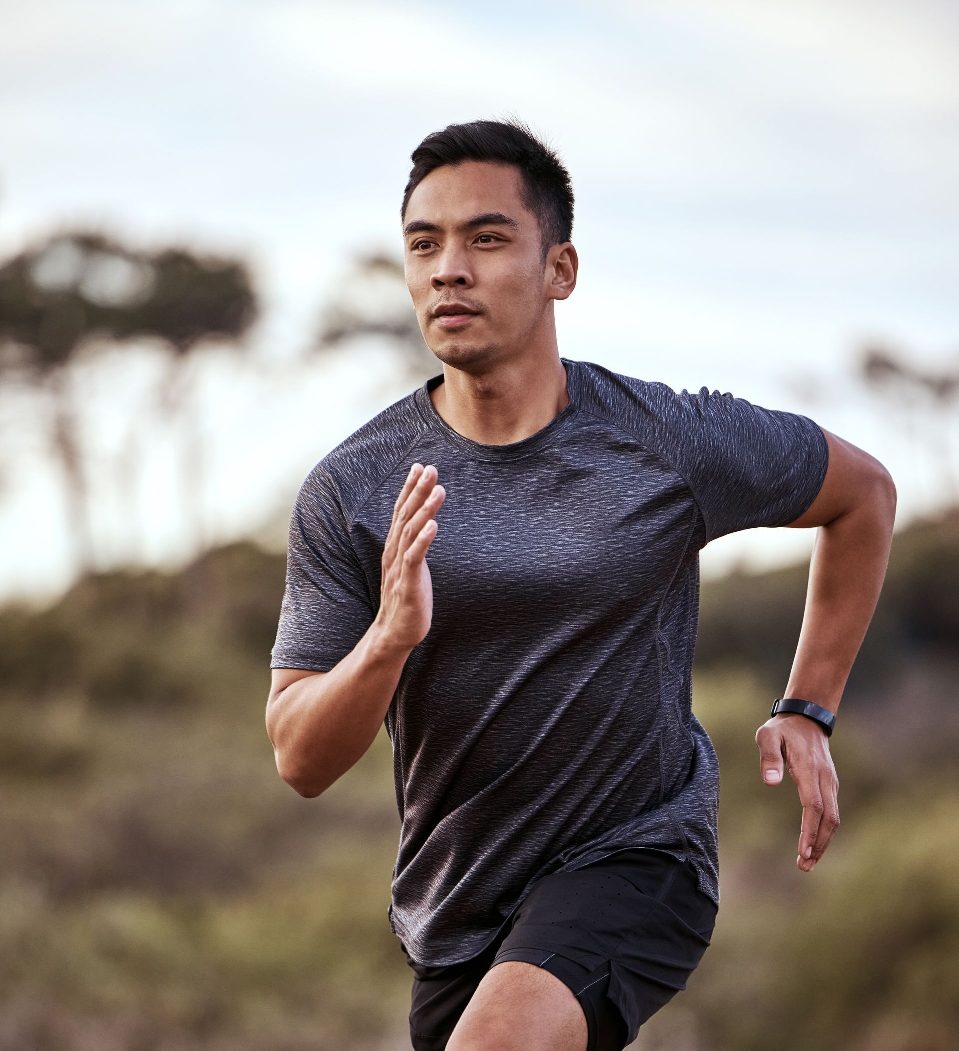 A man in a gray shirt and black shorts is running in a field.
