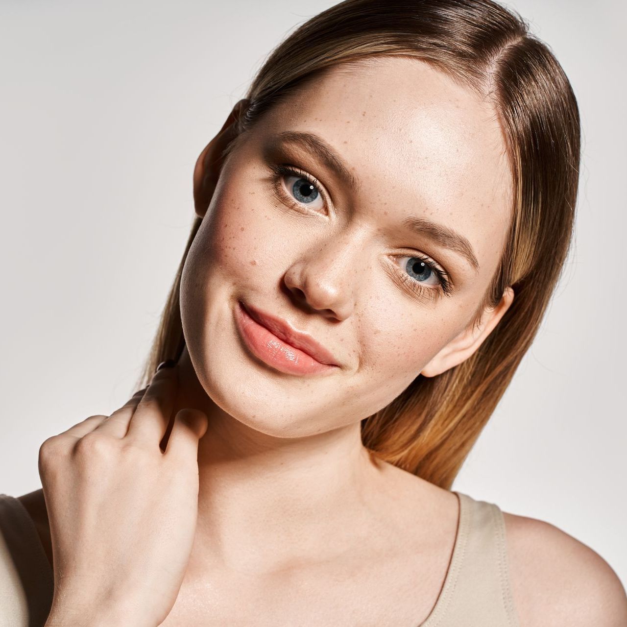 A close up of a woman 's face with her hand on her neck
