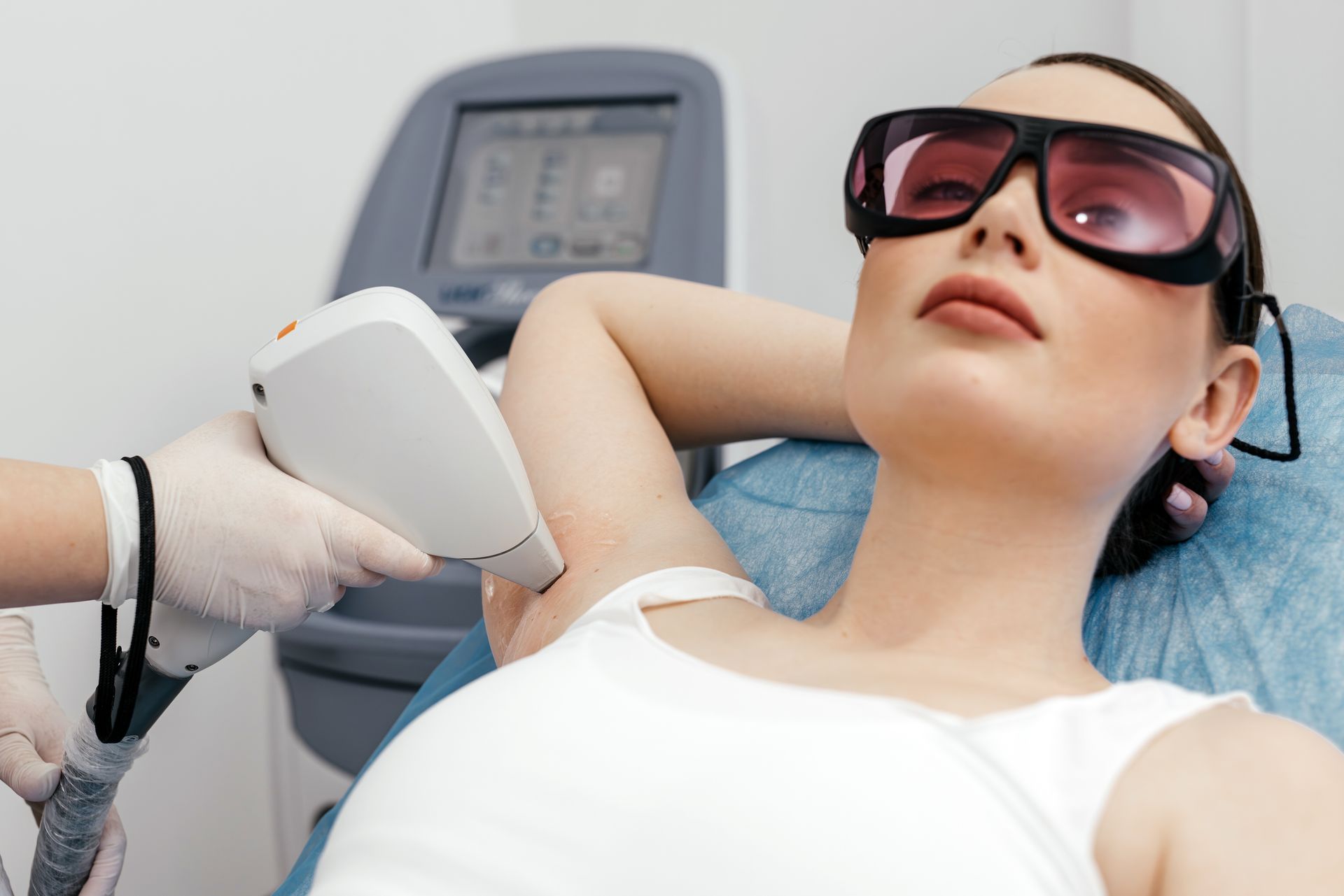 A woman is getting a laser hair removal treatment on her armpit.