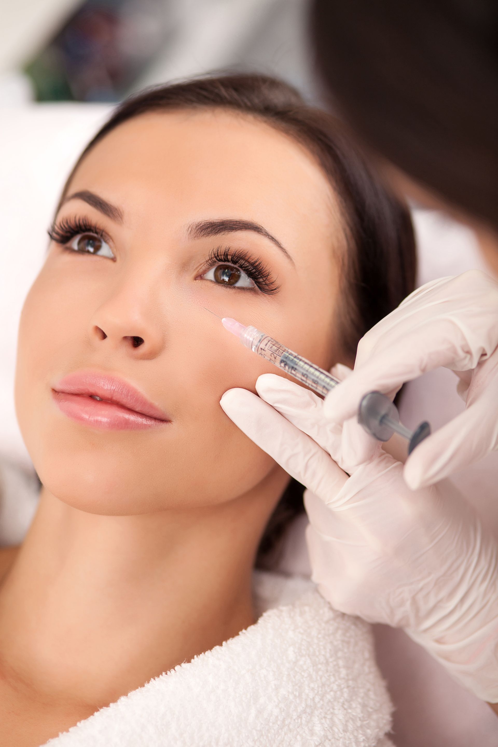 A woman is getting a botox injection in her face