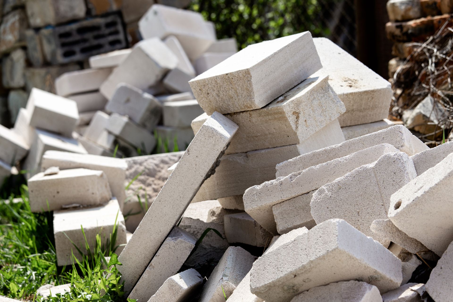 A pile of white bricks is sitting in the grass.