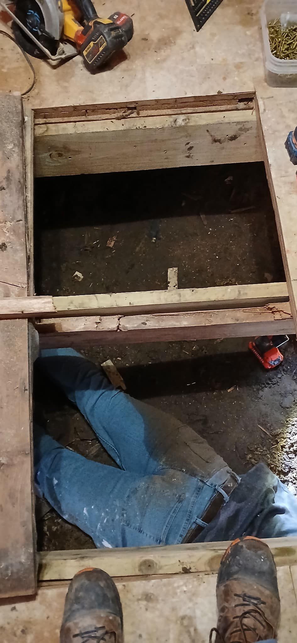 A person is laying in a hole in the floor.