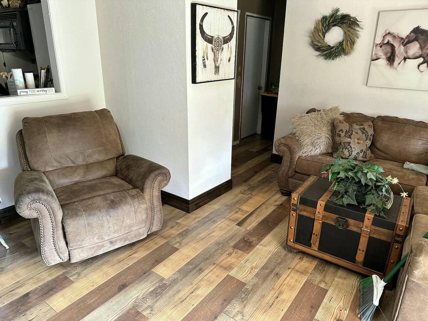 A living room with a couch , chair , coffee table and trunk.