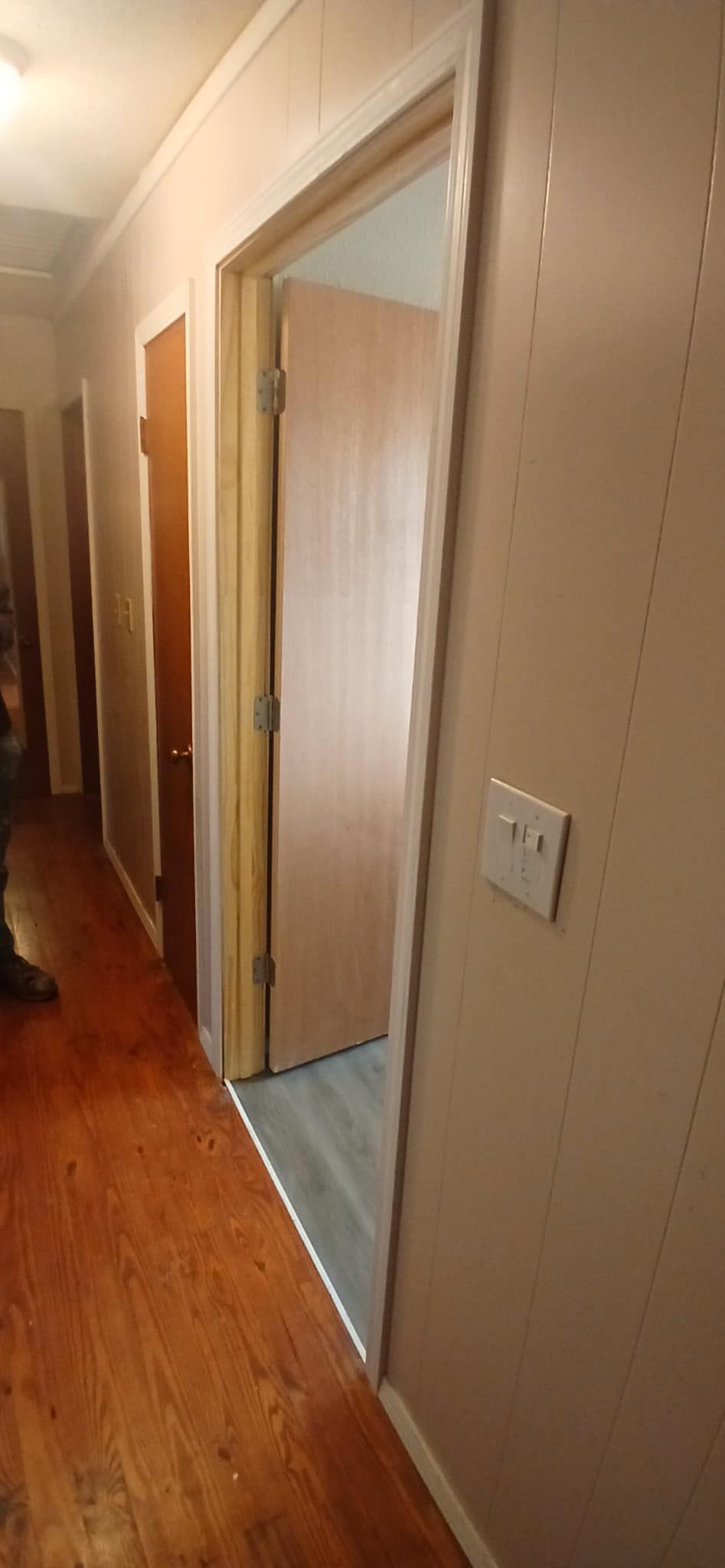 A hallway with hardwood floors and a door that is open.