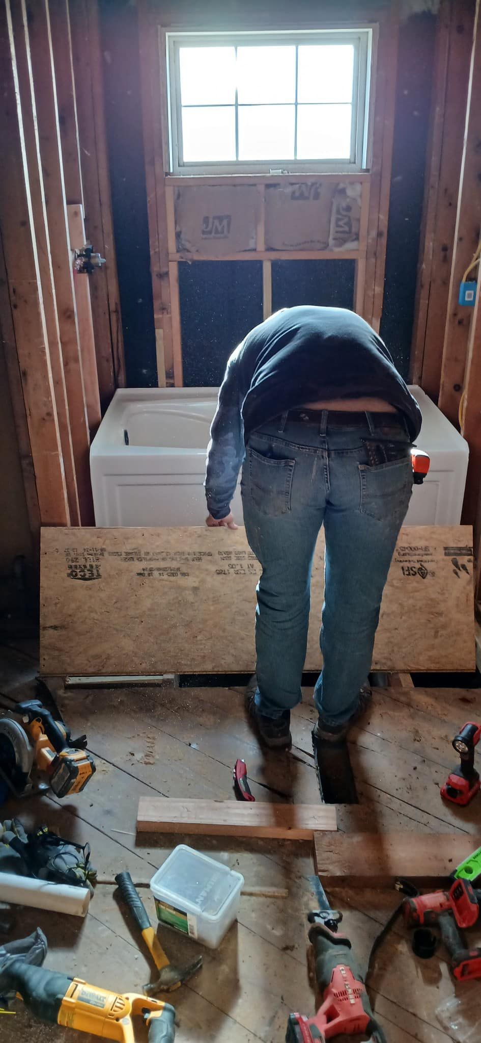 A man is working on a bathtub in a bathroom.