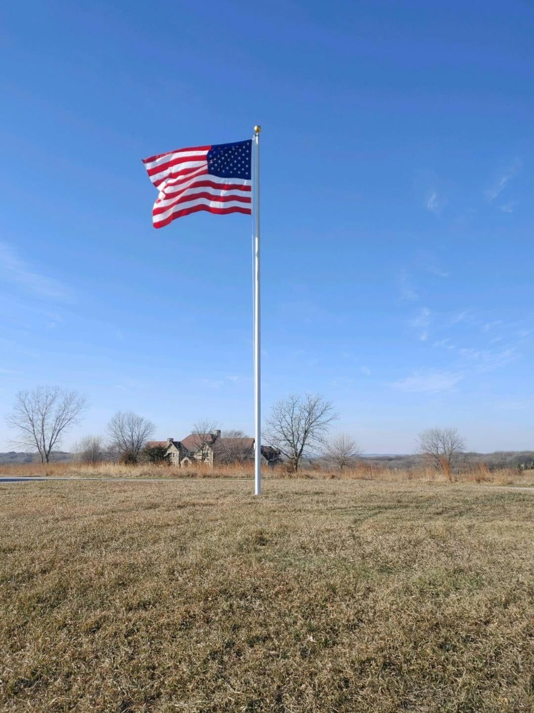 A large american flag is flying in the wind in a field.