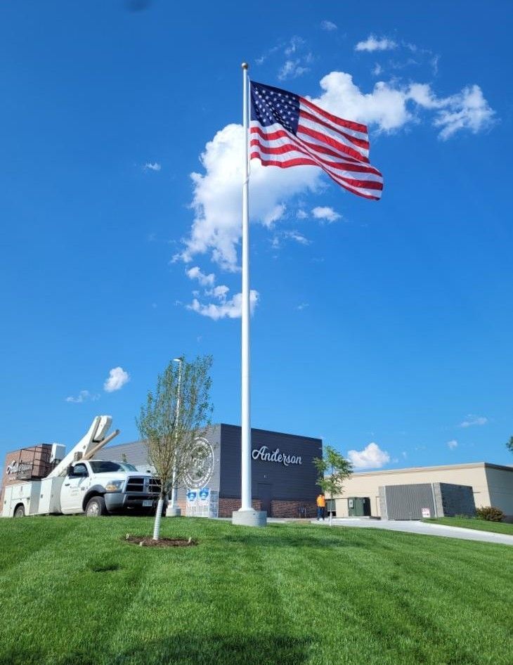 American flag flying on a tall pole outside a building under a bright blue sky.