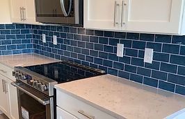 Kitchen with white cabinets, blue subway tile backsplash, and stainless steel appliances.
