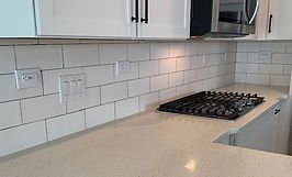 Kitchen with white cabinets, light-colored countertops, and white subway tile backsplash. A gas stovetop is visible.