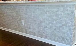 Counter bar with light gray brick-patterned tile, white baseboard, and a power outlet.