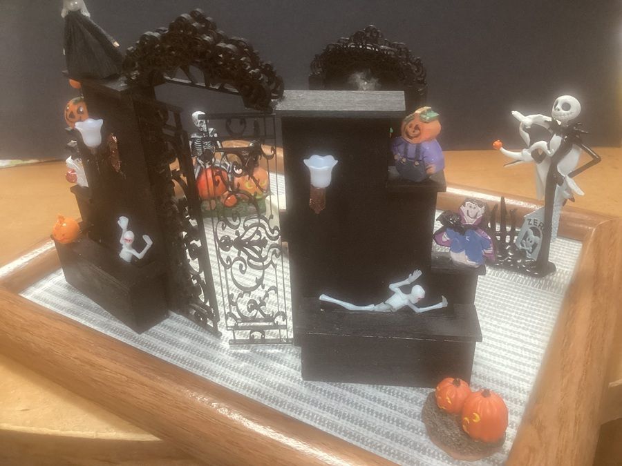 Halloween tabletop display with black haunted house, skeleton, pumpkins, and orange-and-black decorations