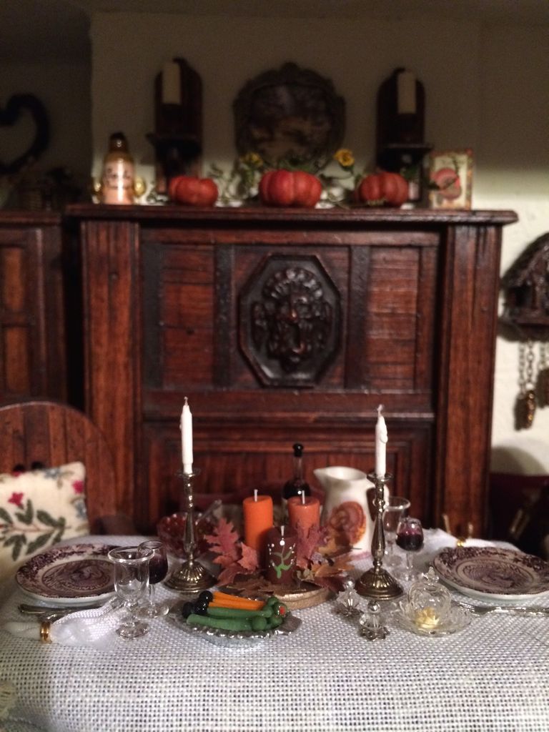 Halloween-decorated dining table with pumpkins, candles, and fall centerpiece in front of a wooden sideboard