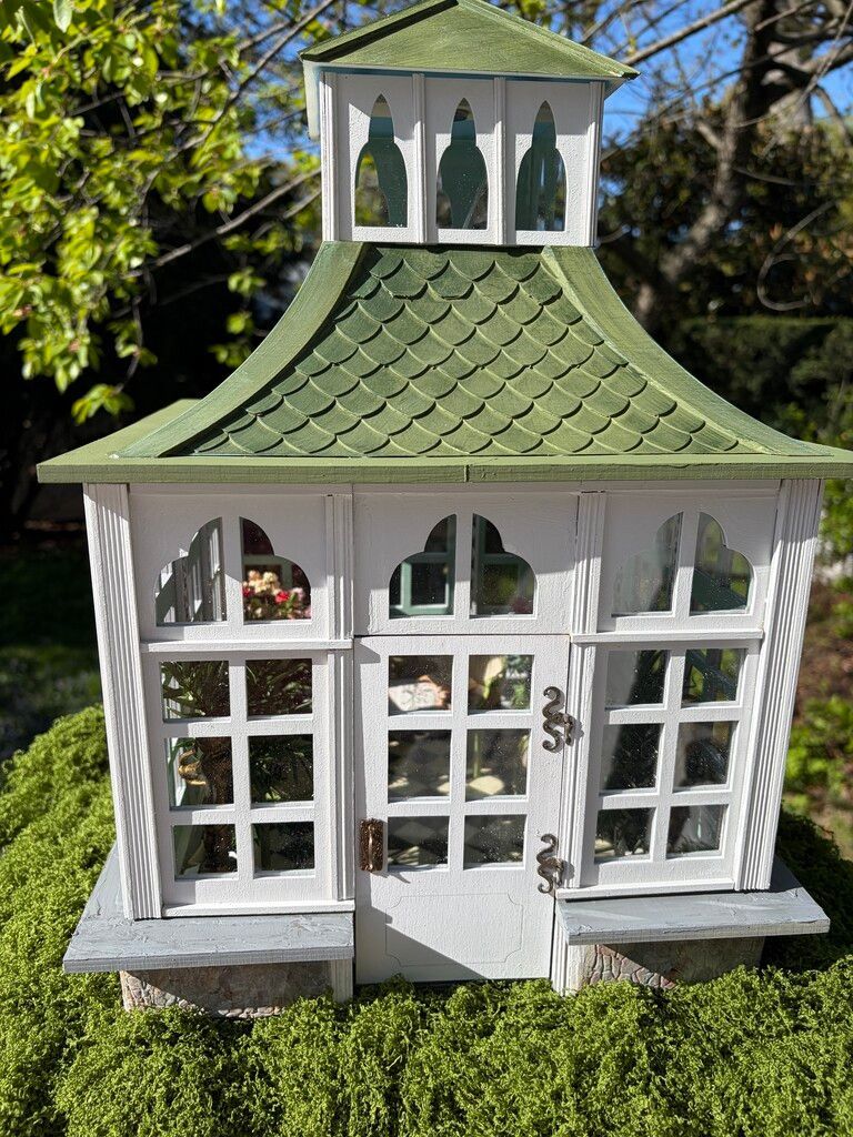 Three white decorative model houses with gray roofs arranged on a wooden table.