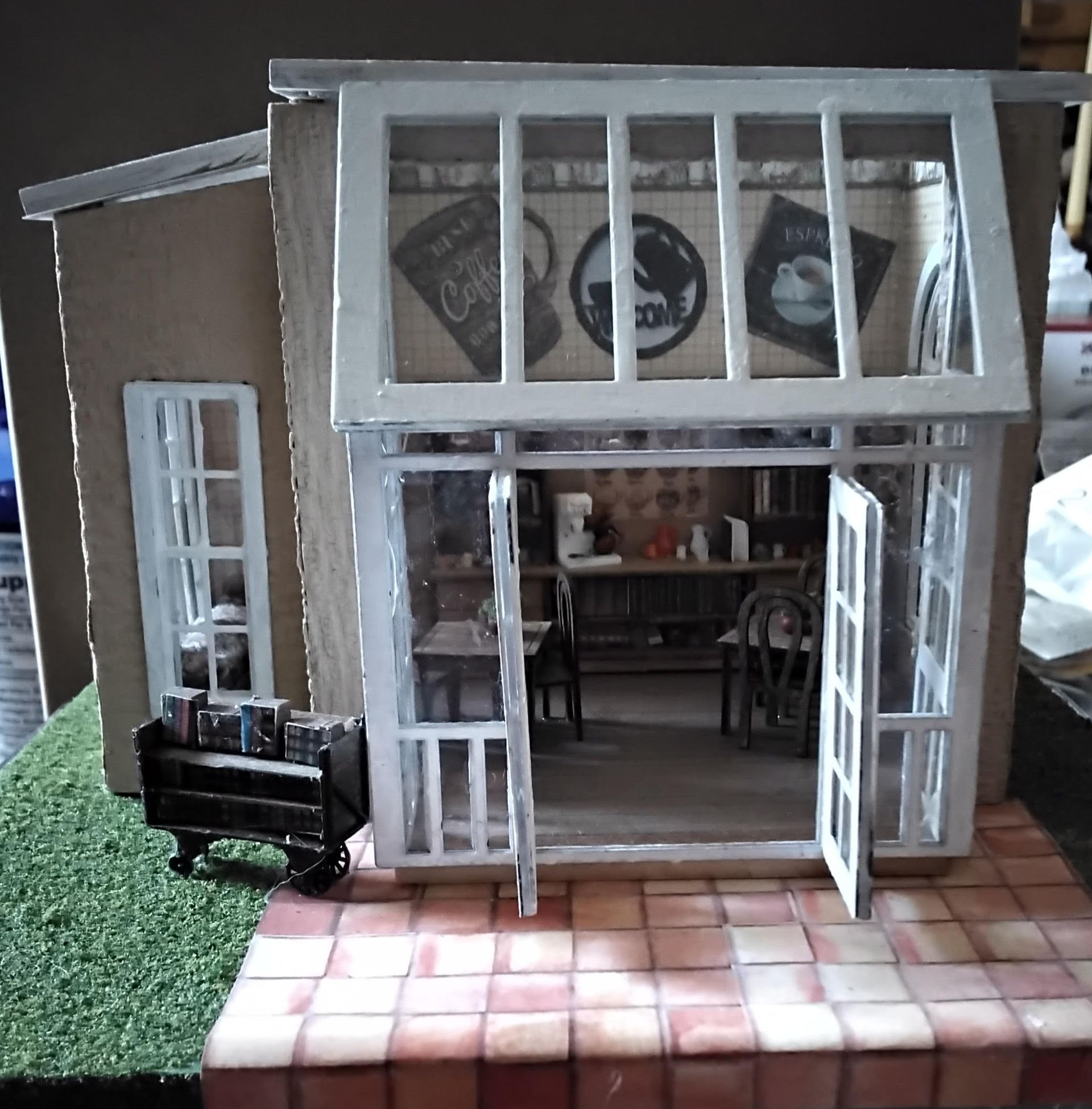 Small model storefront with open white doors, black bench, and tiled front patio.