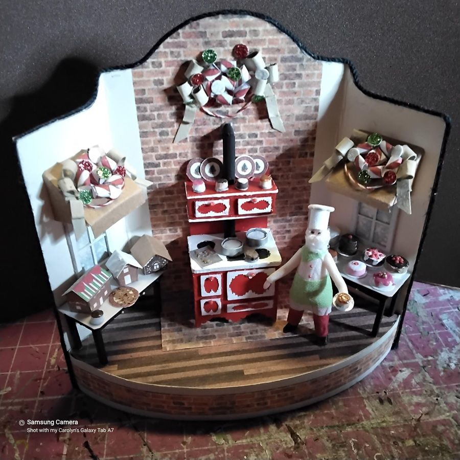 Miniature bakery display with red-and-white decor, shelves of pastries, and a chef figurine on a wooden stage.