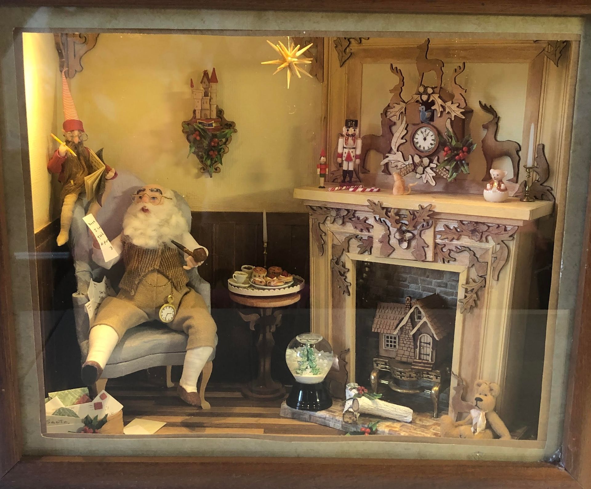 Miniature holiday living room with Santa seated by a fireplace, mantel decorations, and warm lights.