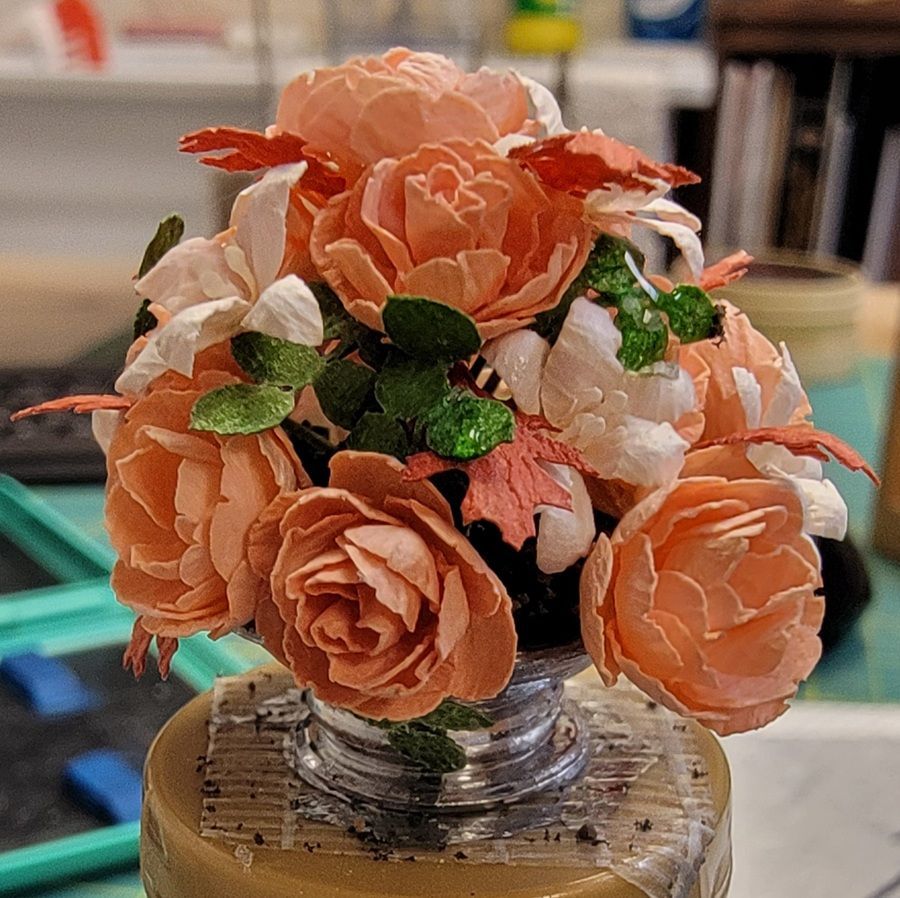 Peach and white flowers arranged in a small glass vase on a table