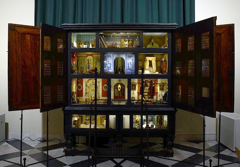 Open display cabinet with illuminated religious icons and folded doors in a gallery setting