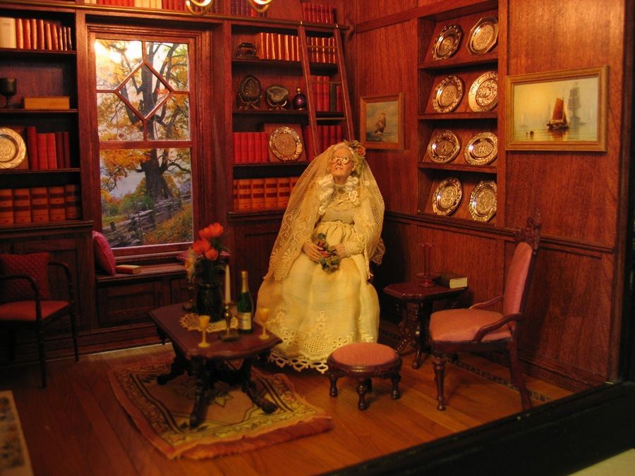 Victorian-style study with a seated mannequin in a cream dress, surrounded by bookshelves and antique furniture.