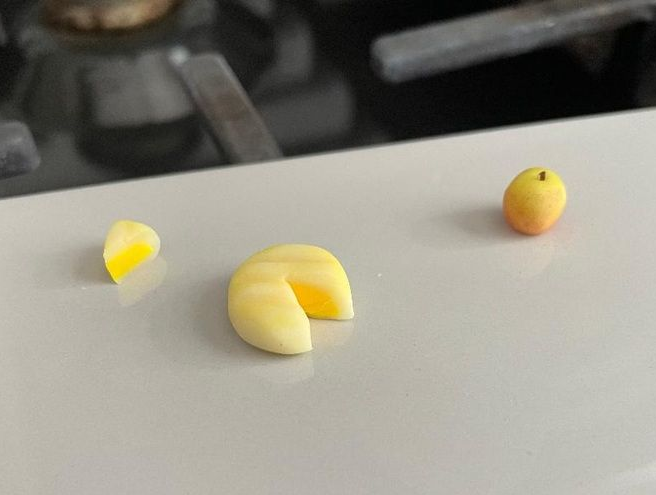 Yellow fruit pieces on a white table, including a sliced apple and a small round fruit