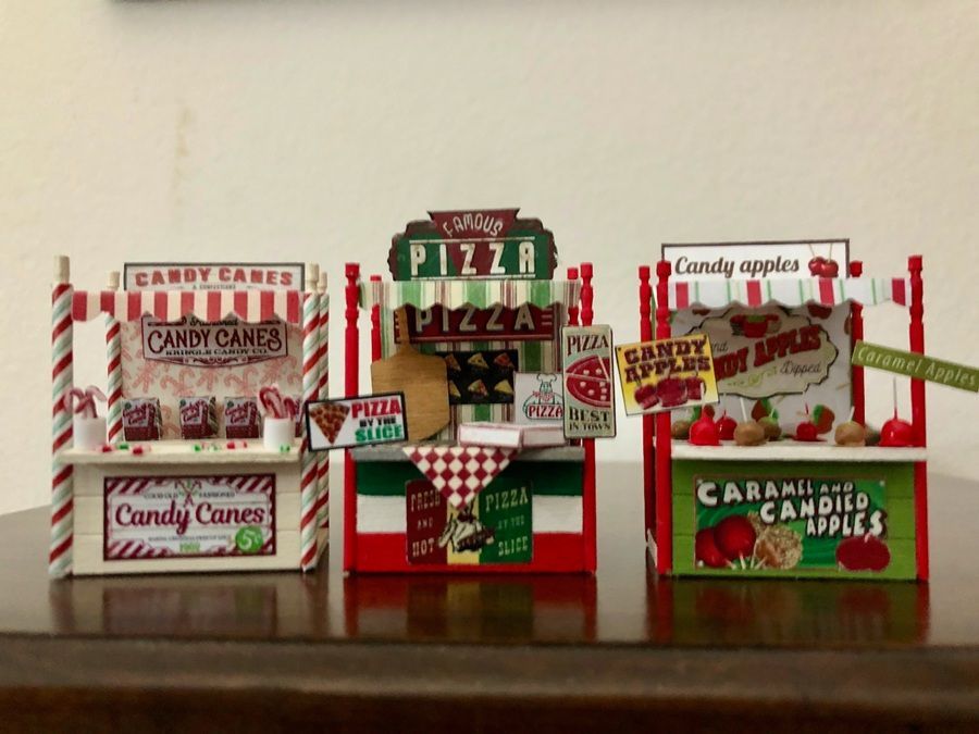 Miniature candy shop display with red-and-white candy boxes and signs for candy, pizza, and apples