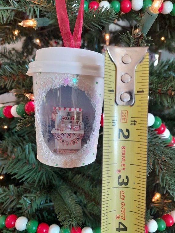 Two wooden egg ornaments open to reveal tiny white snowmen and a snowy forest scene inside