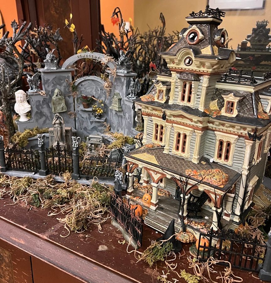 Detailed Halloween miniature village with a haunted Victorian house, tombstones, and black fencing