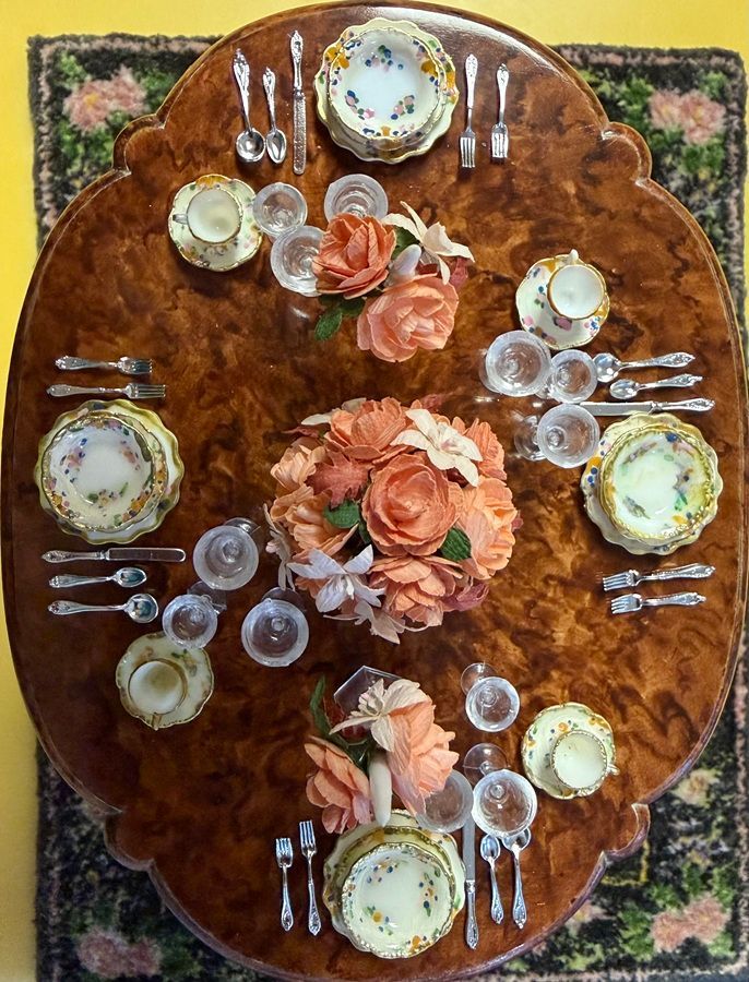 Overhead view of a round floral tablecloth with a set dining table and pink rose centerpiece