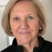 Close-up portrait of a smiling woman with short blonde hair against a light background