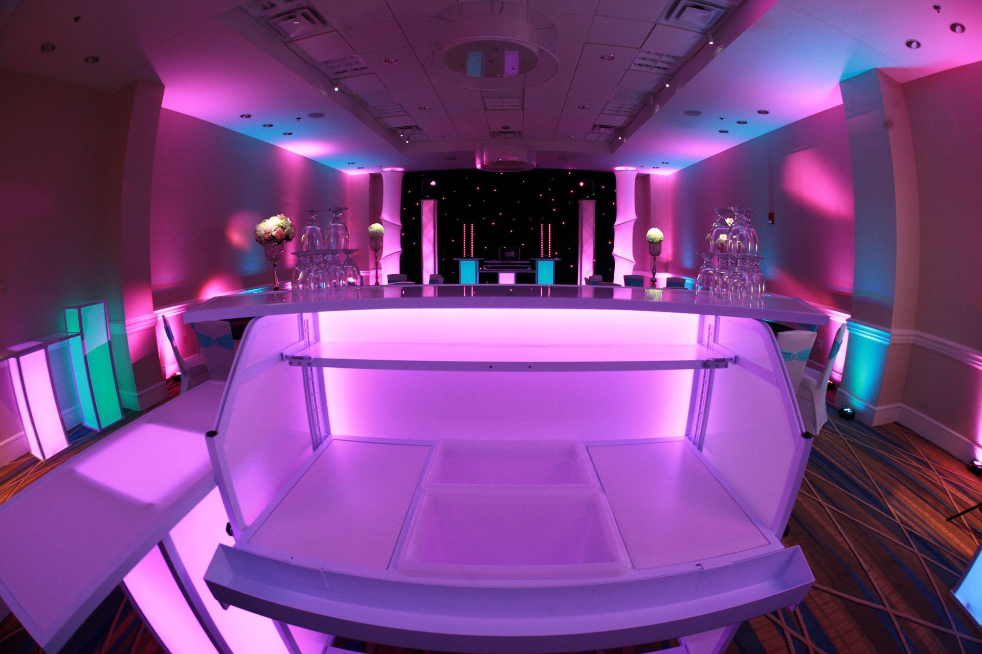 A dj is playing music at a party in a large room.