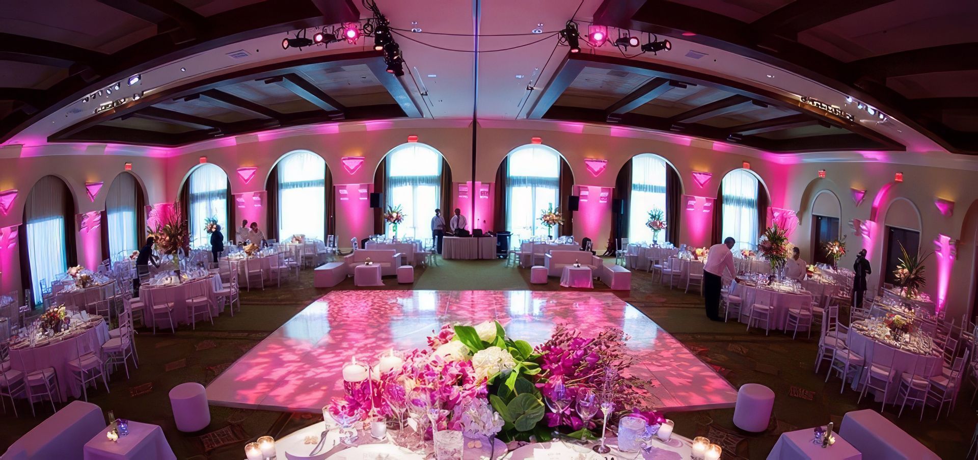 A dj is playing music at a party in a large room.