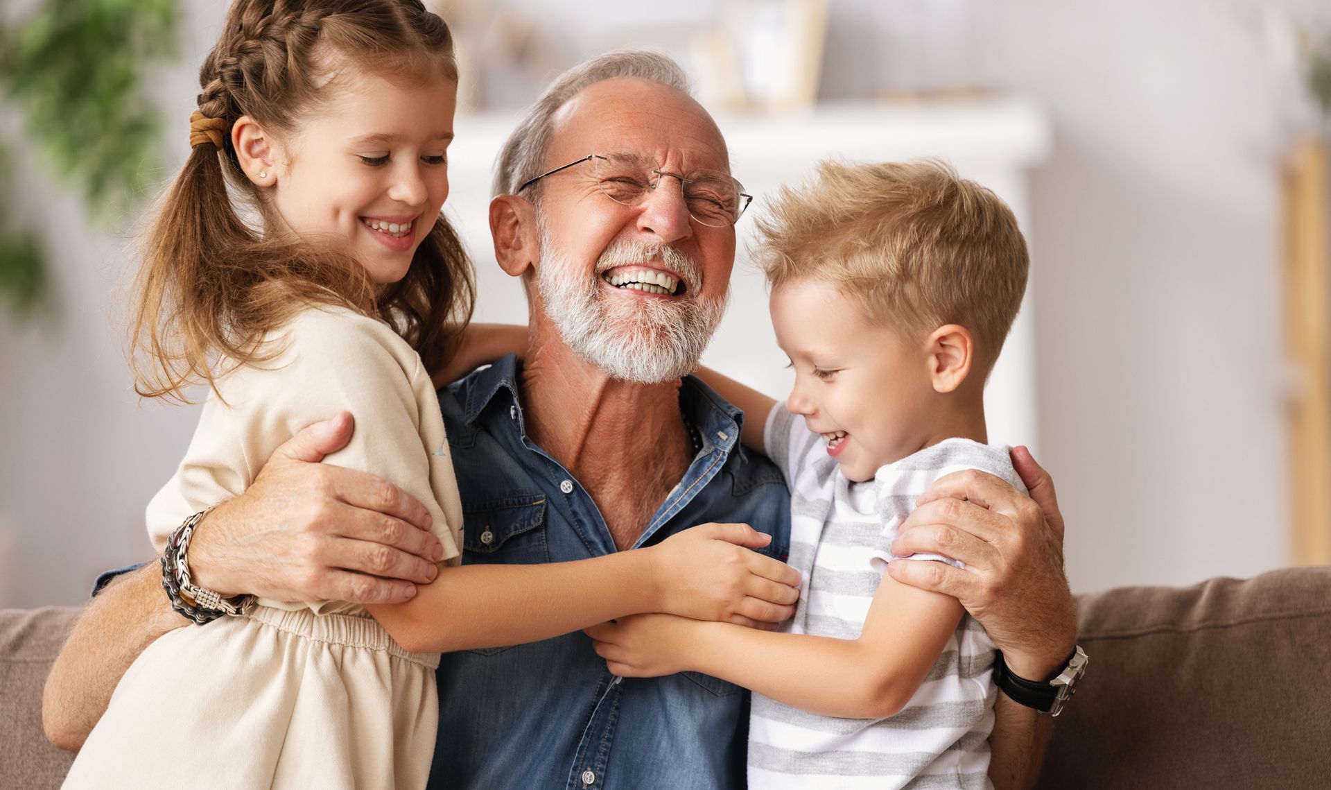 A man and two children are hugging each other on a couch.