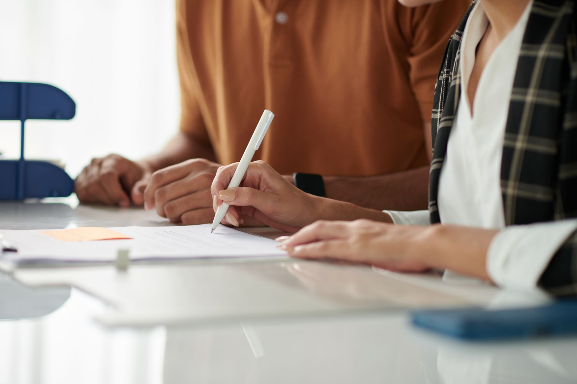 A man and a woman are sitting at a table writing on a piece of paper.