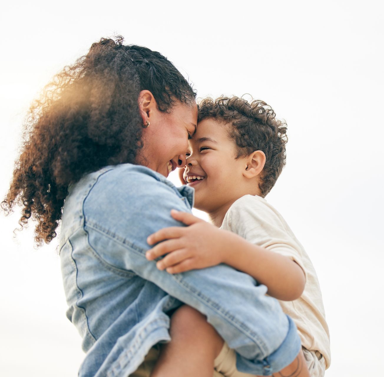 A woman is holding a child in her arms and they are smiling at each other.