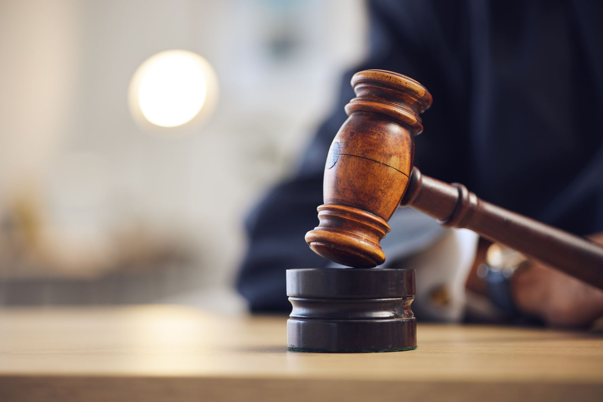 A wooden judge 's gavel is sitting on a wooden table.