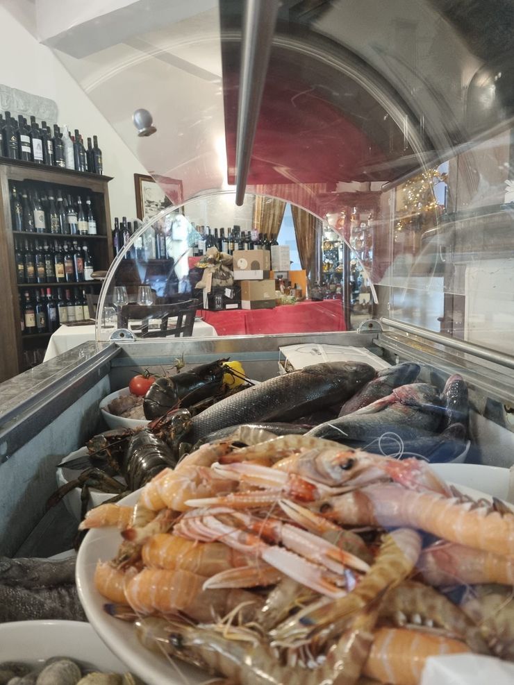 Vetrina espositiva di frutti di mare freschi, tra cui gamberi e cozze, al bancone di un ristorante.
