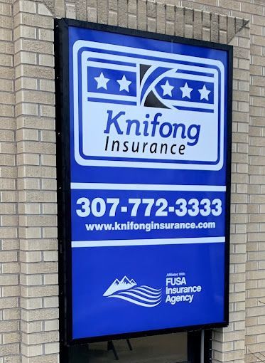 A sign for knifong insurance is hanging on a brick wall.