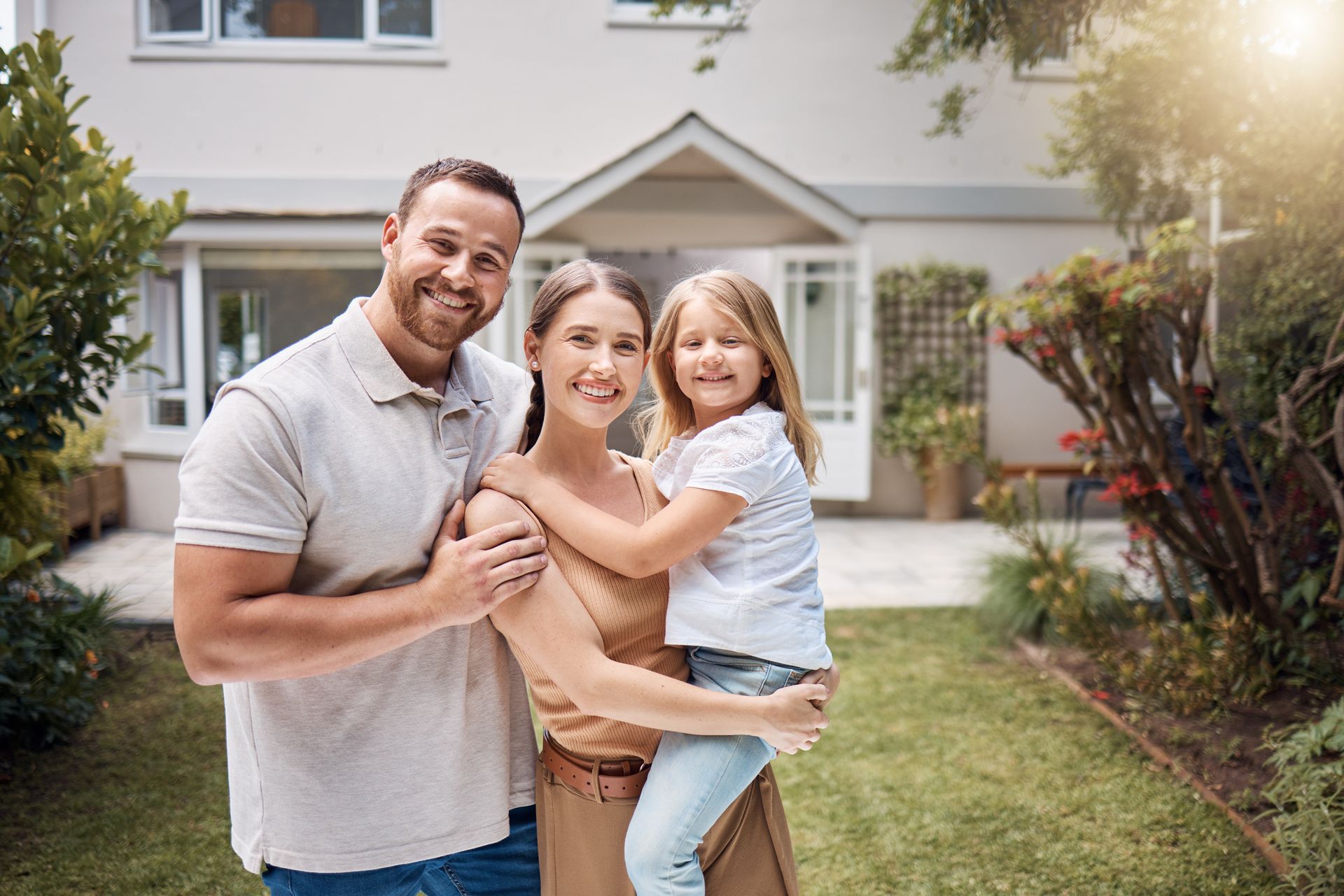 A family is posing for a picture in front of their new home.